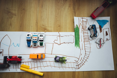 A top view of toy cars on the drawn railroad on white paperの写真素材