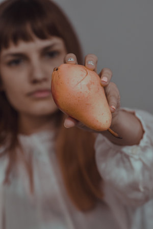 A vertical shot of a young Caucasian female showing a red pearの写真素材