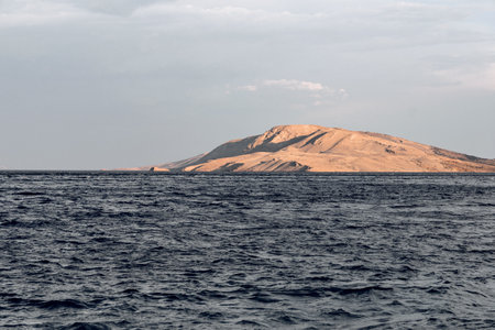 A closeup shot of a small island on the sea against cloudy sky backgroundの写真素材