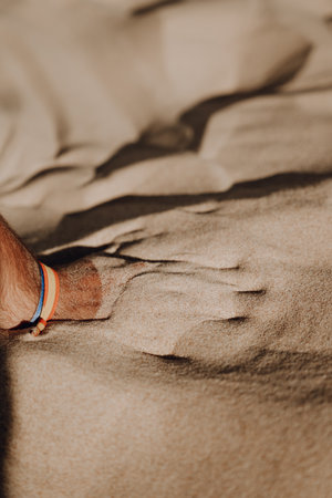 A vertical shot of a person playing with the sand at the beachの写真素材