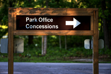 A soft focus of a wooden sign pointing to the direction of the park office and concessionsの写真素材