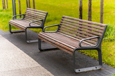 A sunny park with a well-kept field of grass and benches on pavementの写真素材