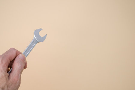 A closeup shot of a hand holding an open wrench isolated on pink backgroundの写真素材