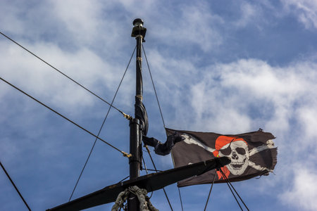 A low angle shot of a pirate flag under a cloudy skyの写真素材