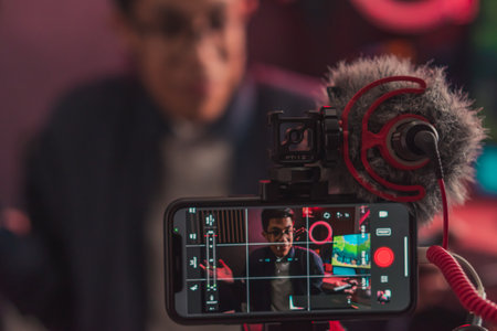 A closeup shot of a young gamer male going live on a professional setup with a phone and a microphoneの写真素材