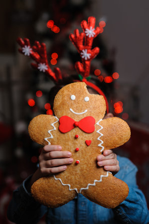A vertical shot of a gingerbread cookie with Christmas decorations on a blurred background