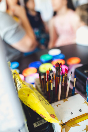 A box of various paintbrushes with a watercolor set in the backgroundの写真素材
