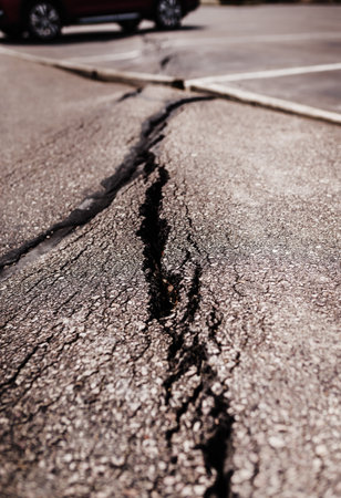 A vertical shot of a cracked asphalt road on a sunny dayの写真素材