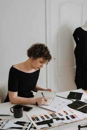 A beautiful young Caucasian businesswoman and fashion designer reviewing her clothes design sketchesの写真素材