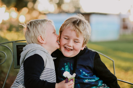 Two happy boys from Australia sitting on a bench and having funの写真素材