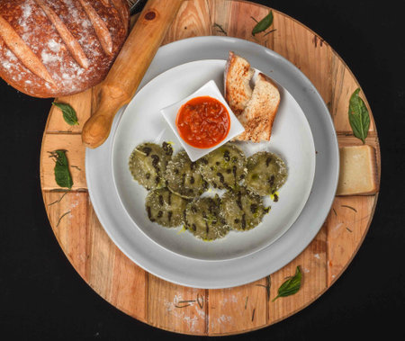 A top view of tasty green ravioli pasta with freshly baked bread and rolling pin on a wooden boardの写真素材