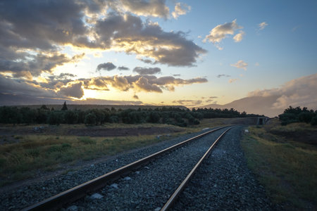 A mesmerizing view of sunset with train rails and a beautiful cloudy skyの写真素材