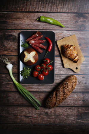 A top view of bacon rolls with fresh vegetables, croissant, and bread on a kitchen tableの写真素材