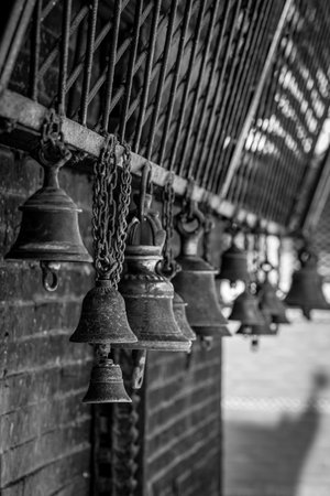A grayscale shot of hanging bellsの写真素材