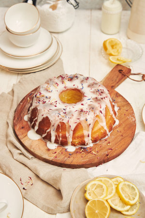 A vertical shot of a delicious citron cake with glaze and flower on top on a white table