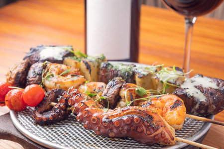 A top view of grilled seafood sticks with a glass of red wine