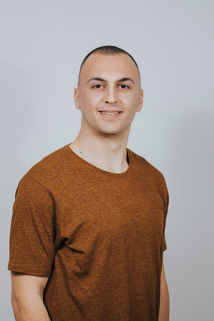 A handsome Caucasian male posing against a white wall