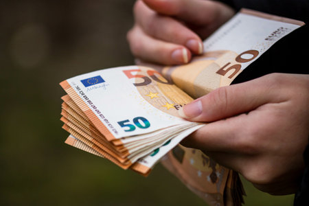 A closeup of female hands counting EURO banknotes - world money, inflation and economy conceptの写真素材