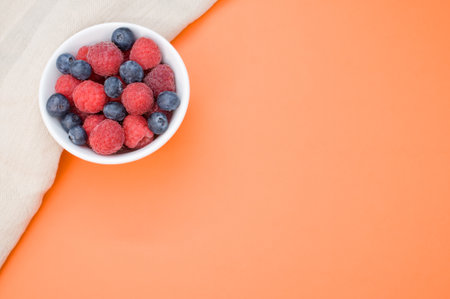 A top view of fresh blueberry and raspberry on a white bowlの写真素材