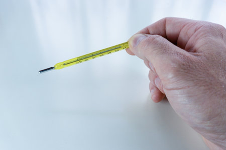 A closeup shot of a hand holding a yellow thermometer
