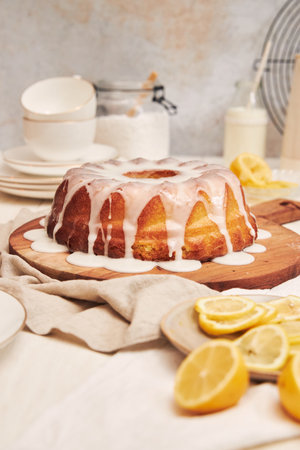 A vertical shot of a delicious citron cake with glaze and flower on top on a white tableの写真素材