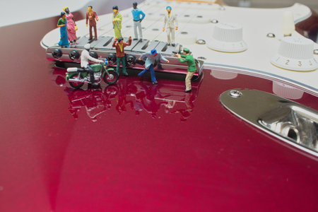 A closeup shot of small figures of people on an electric guitarの写真素材