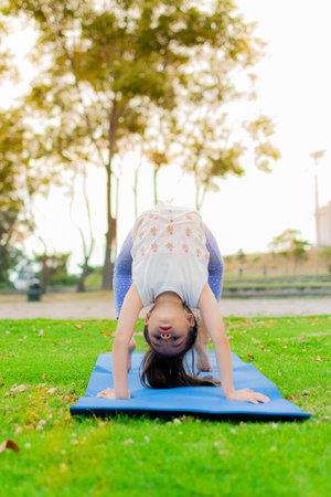 A vertical shot of a cute Latin girl practicing yoga in a park