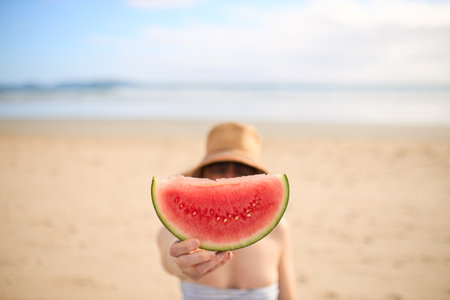 A girl on the beach showing a piece of watermelonの写真素材