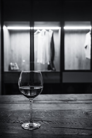 A vertical grayscale shot of glass on the wooden table inside the closetの写真素材
