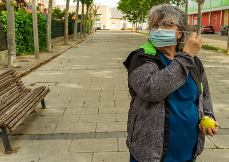 obese senior woman doing sports in the park slimming diet with face maskの写真素材