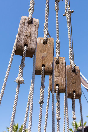 A vertical shot of several old ship pulleys on the background of the blue sky