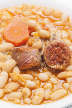 A vertical shot of potage of beans with chorizo, potatoes in a white bowlの写真素材