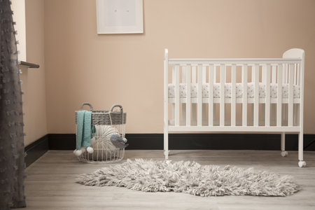 A shot of minimalistic sunny baby's room interior with child's bed, small round carpet, and elegant basket.の写真素材