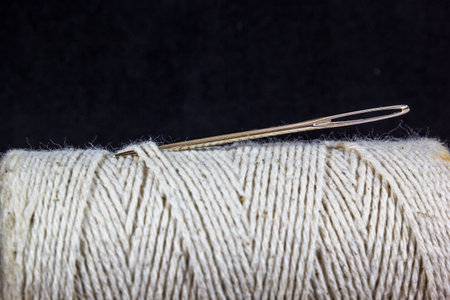 A closeup shot of a twine roll with a needle on a black backgroundの写真素材