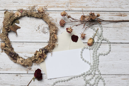 A top view of a wreath with dried flowers envelopes and beadsの写真素材