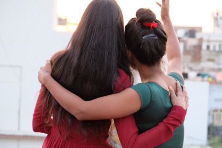 A back view of two young Indian females hugging each otherの写真素材