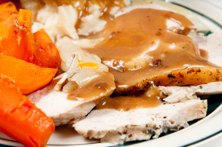A closeup of white roasted meat with sauce and carrots on the plateの写真素材