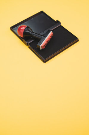 The black ink pad with a rubber stamp isolated on yellow backgroundの写真素材