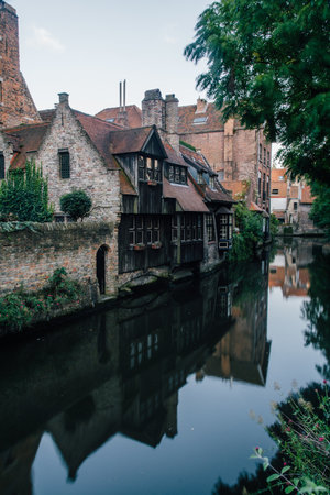 A vertical shot of a canal surrounded by buildings in Belgiumの写真素材