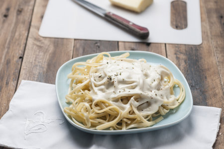 A high angle shot of a plate of spaghetti with cheese sauce on a wooden tabの写真素材