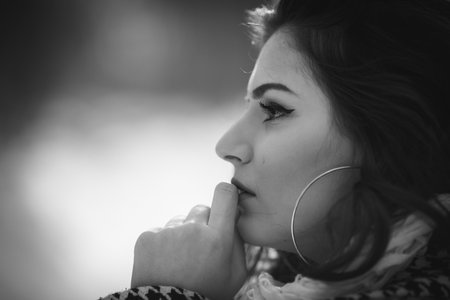A grayscale shot of a beautiful Caucasian woman in a winter coat posing on the snowの写真素材