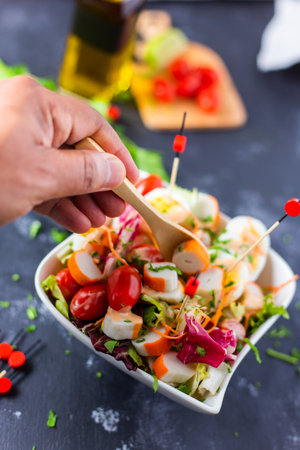 A closeup of a person putting a spoon in the freshly made L'Oceane salad in a bowlの写真素材