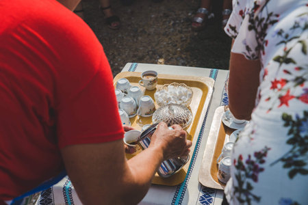 A person pouring Turkish coffee in cups on a tray outdoorsの写真素材