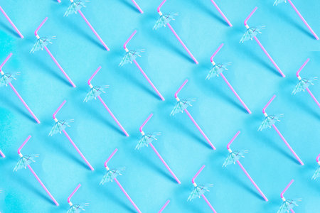 A top view of pattern cocktail flexible straw with umbrella, on a light blue background, straws for summer cocktails.の写真素材