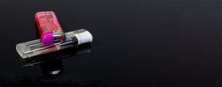 A panoramic shot of pink and white gas lighters on a black reflecting backgroundの写真素材