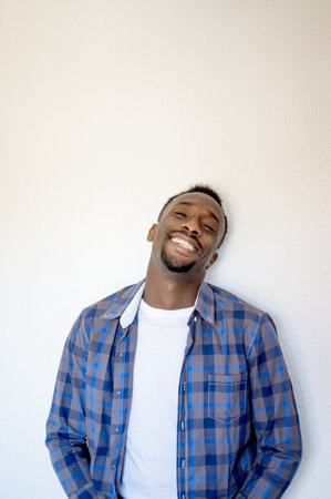 A vertical shot of a happy handsome Black man posing wearing a blue shirt