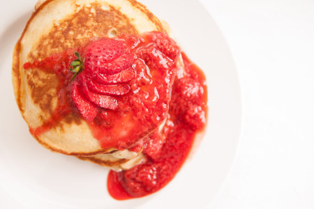 a stack of strawberry pancakes with butter, syrup and fresh berriesの写真素材
