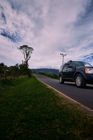 A vertical shot of a black modern car driving on the empty roadの写真素材