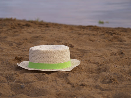 Floppy straw hat left by water side in the sand medium shotの写真素材
