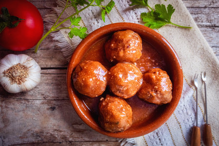 Homemade meatballs, with sauce, in a clay pot and a wooden tableの写真素材